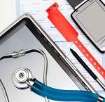 Medical tray with a stethoscope inside next to a hospital band on paperwork