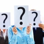 Three people holding up question mark signs in front of their faces