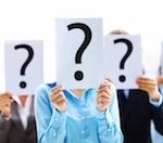 Three people holding up large question mark signs in front of their faces