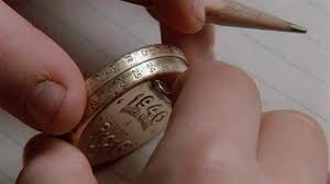 Kids hands holding two gold coins and a pencil over notepad