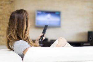 woman changing channels on TV