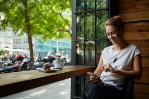 woman having coffee while on iPhone