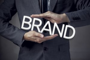 Man in suit holding white "Brand" block letters