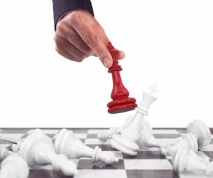 chess board and red piece knocking over white pieces