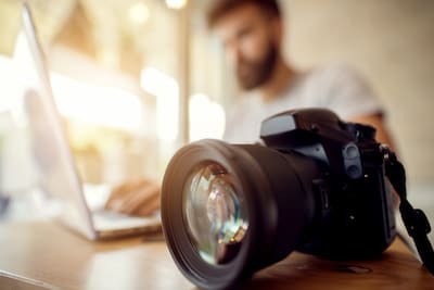 Focused photography camera with blurry background of a man on a computer 