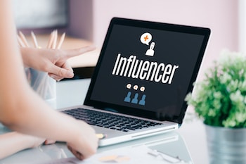 Person pointing to laptop displaying "Influencer" on the screen