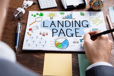 Person in a suit drawing a "Landing Page" sketch at a desk