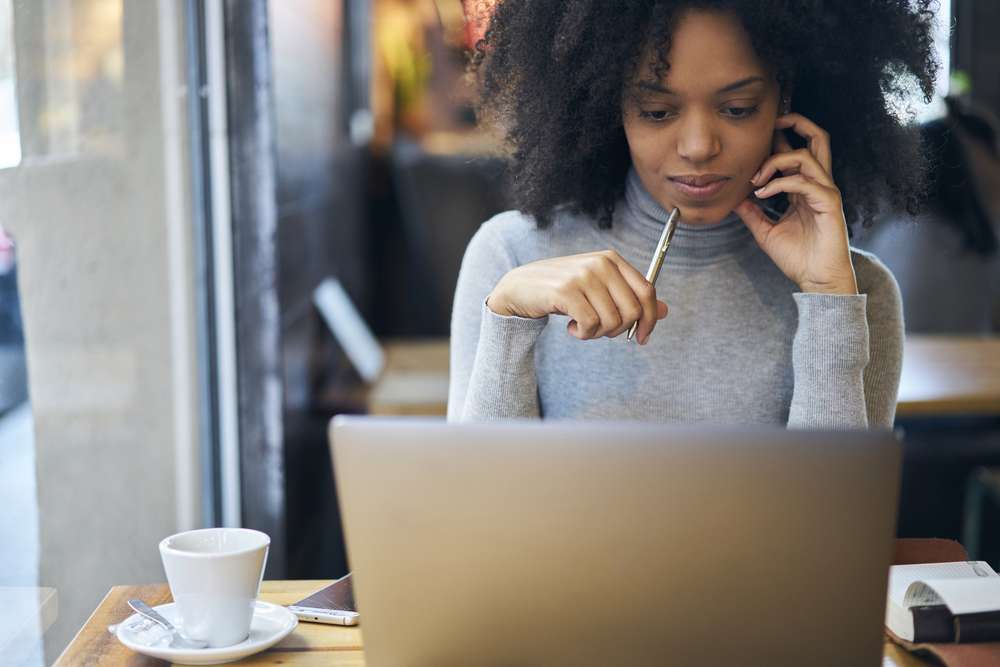 Woman looking intently at laptop screen in a coffee shop