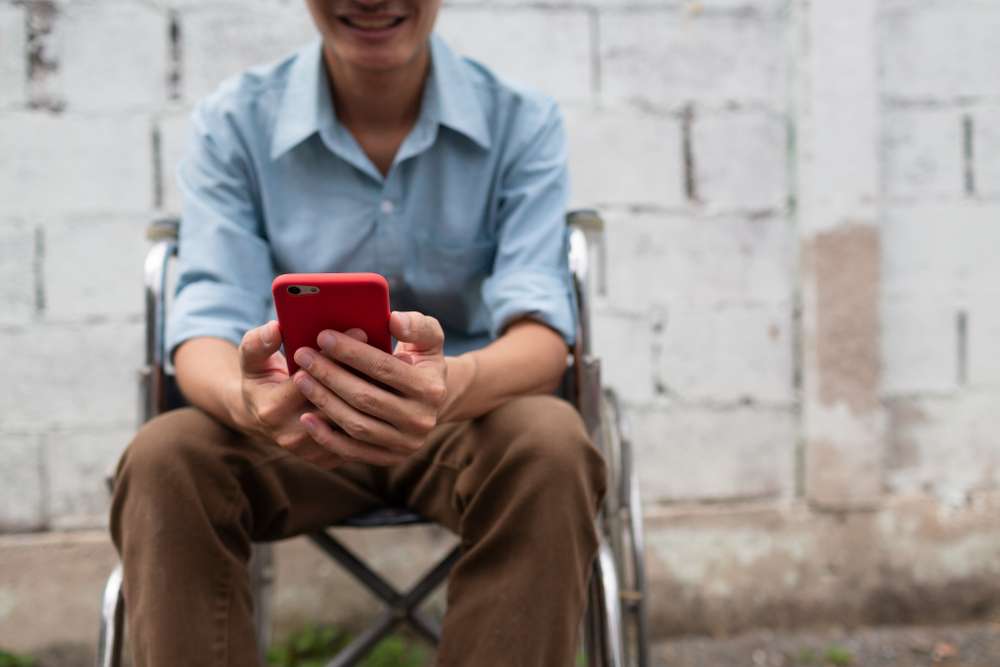 man in wheelchair checking mobile phone video