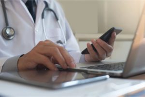 Doctor performing telemedicine and telehealth with laptop, tablet and cell phone