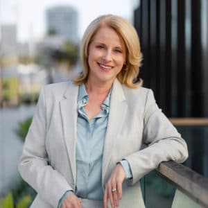 Female CEO posing for a photo with the office building and river behind her.