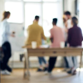 People standing in a circle in front of a whiteboard having a meeting